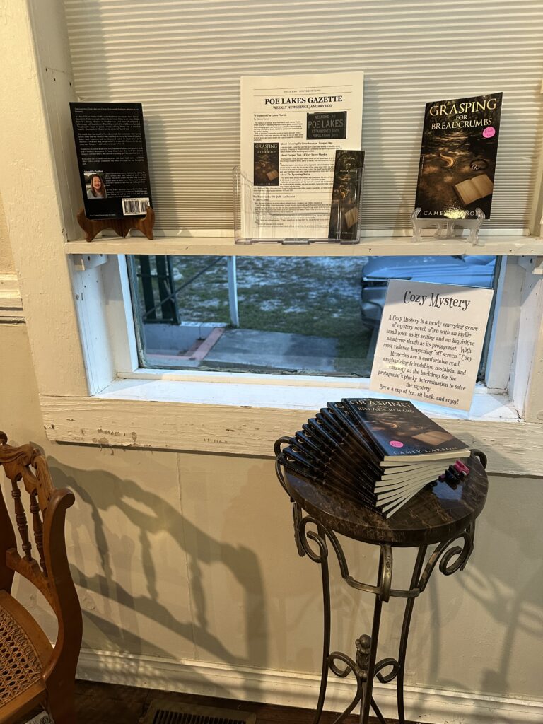 Image of Camey Carson's "Grasping for Breadcrumbs" stacked for purchase and signing underneath a copy of the free marketing newsletter giveaway.